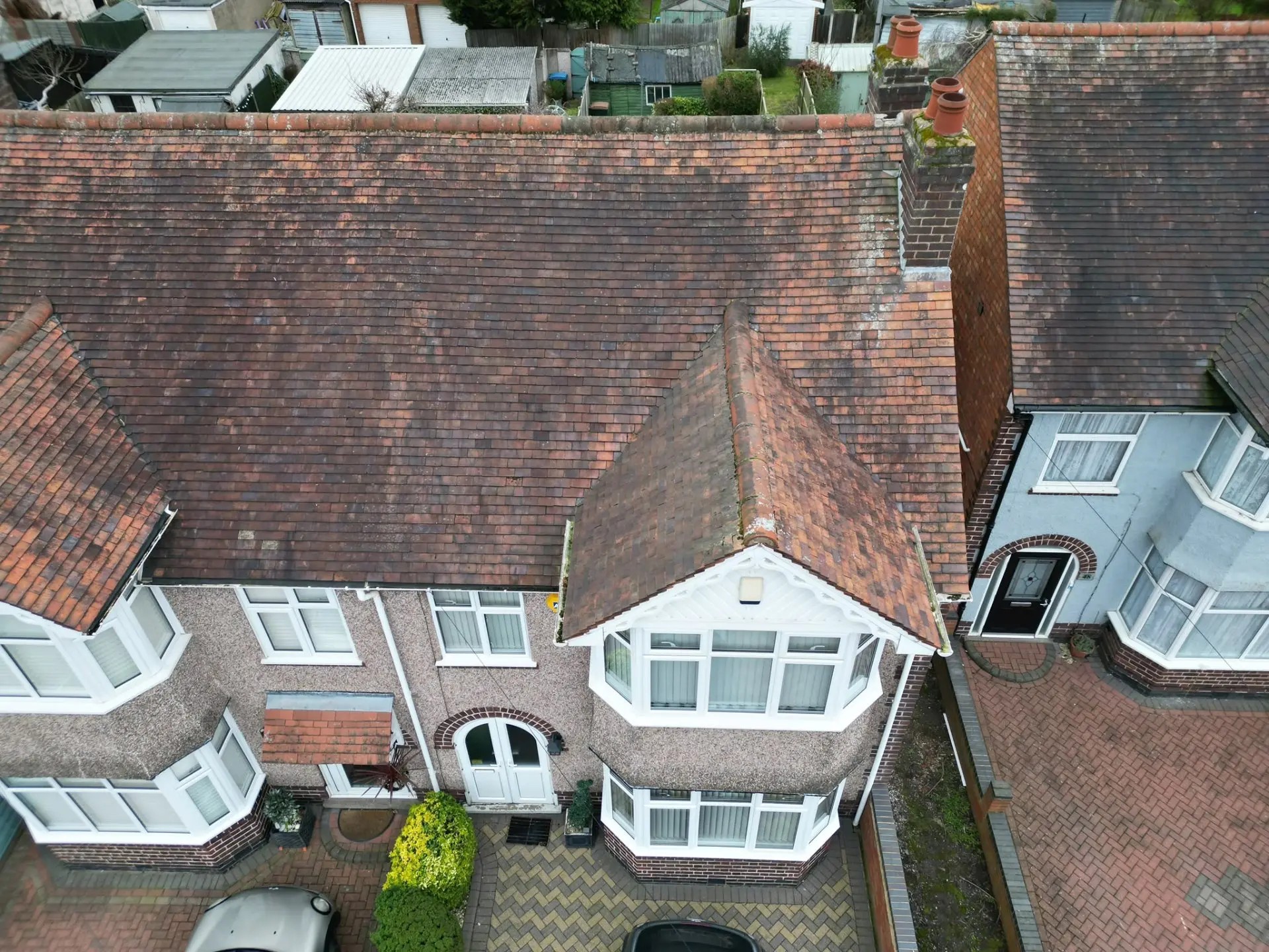 Aerial view of a worn red clay tiled terraced roof with weathered bay gable before re-roofing in Coventry