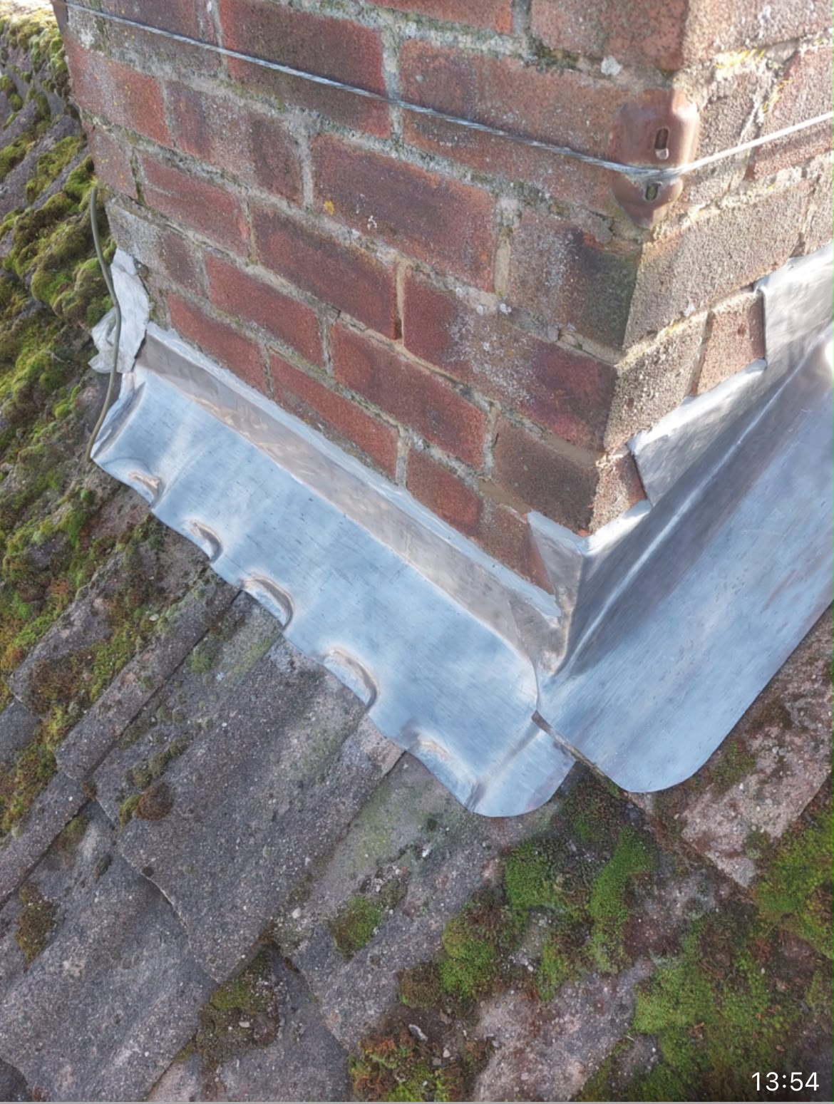 Hand-formed lead flashing installed around a brick chimney base
