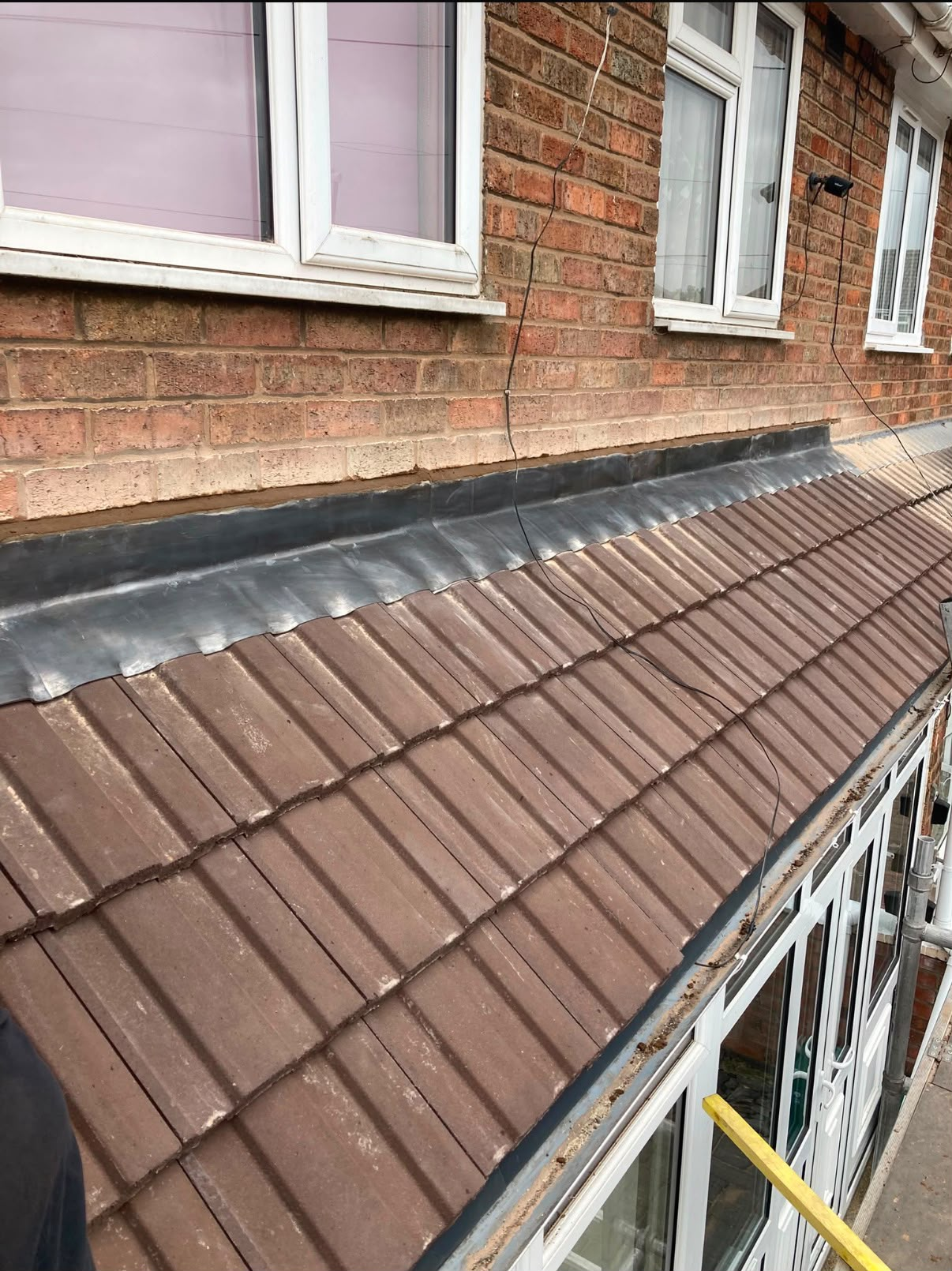 New lead flashing and brown tiled lean-to roof above a conservatory