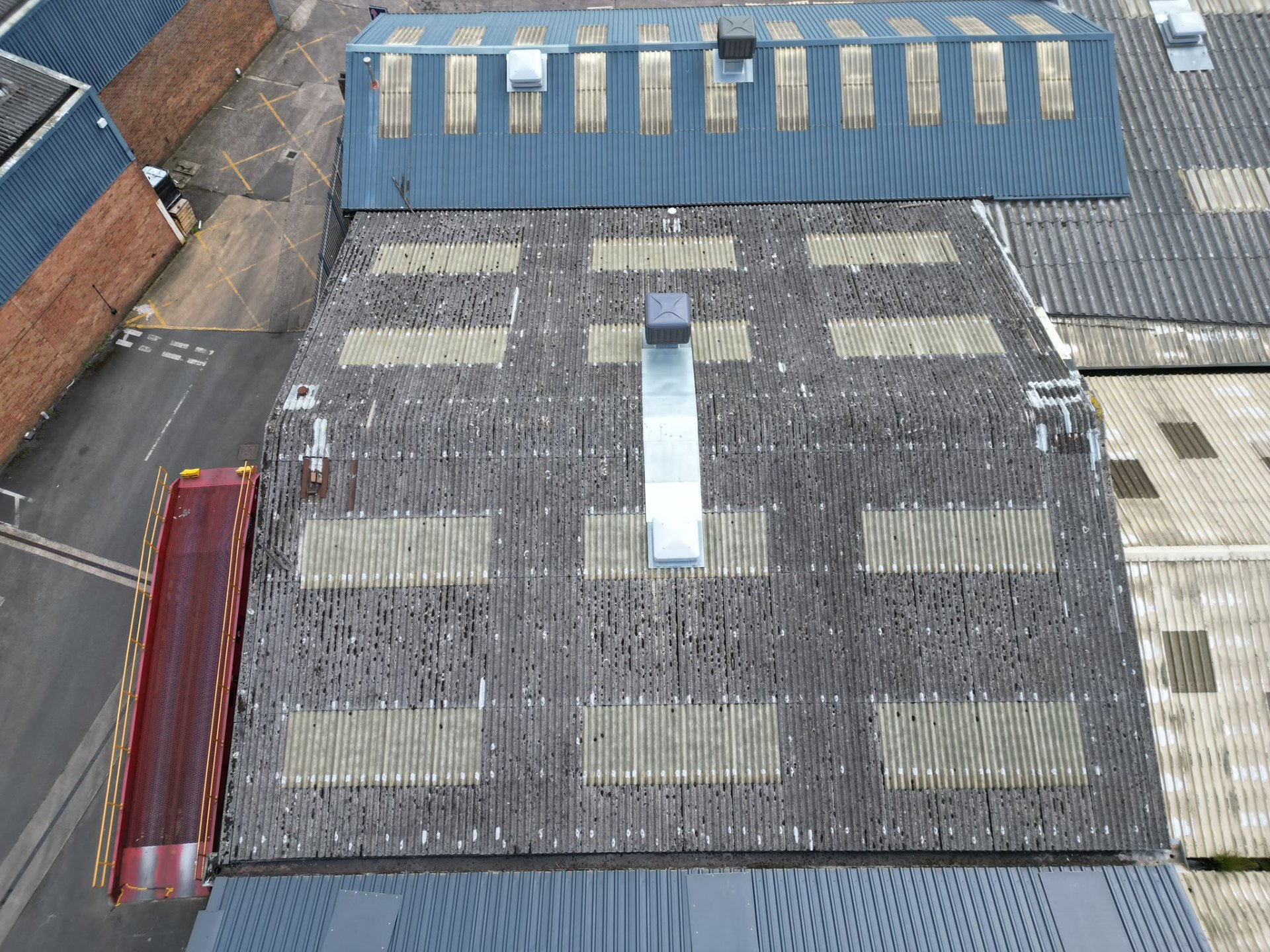 Aerial view of weathered industrial roof with moss growth before refurbishment