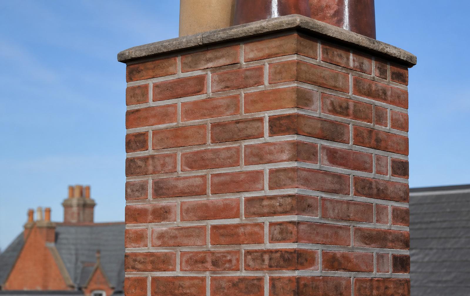 Close-up of a British red-brick chimney with freshly repointed light grey mortar joints