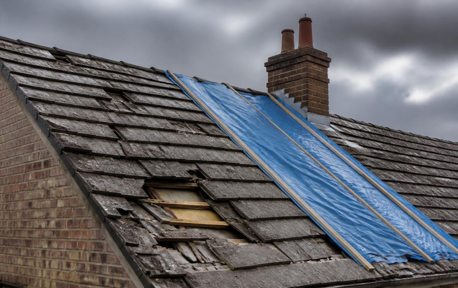 British pitched roof with slipped tiles and a blue tarpaulin temporary cover after storm damage, Coventry emergency roofing